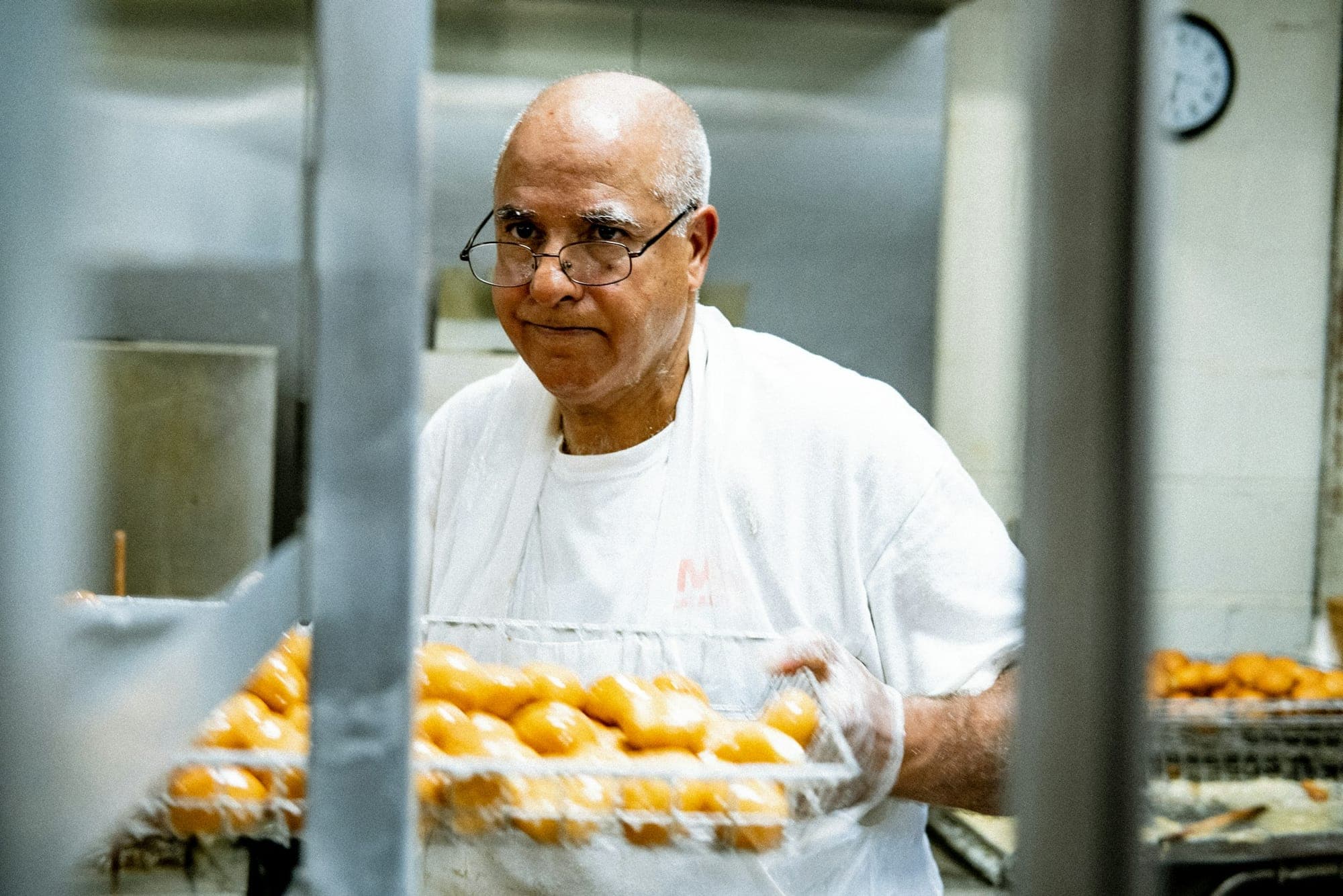 A baker carrying a tray of fresh pastries through a bakery