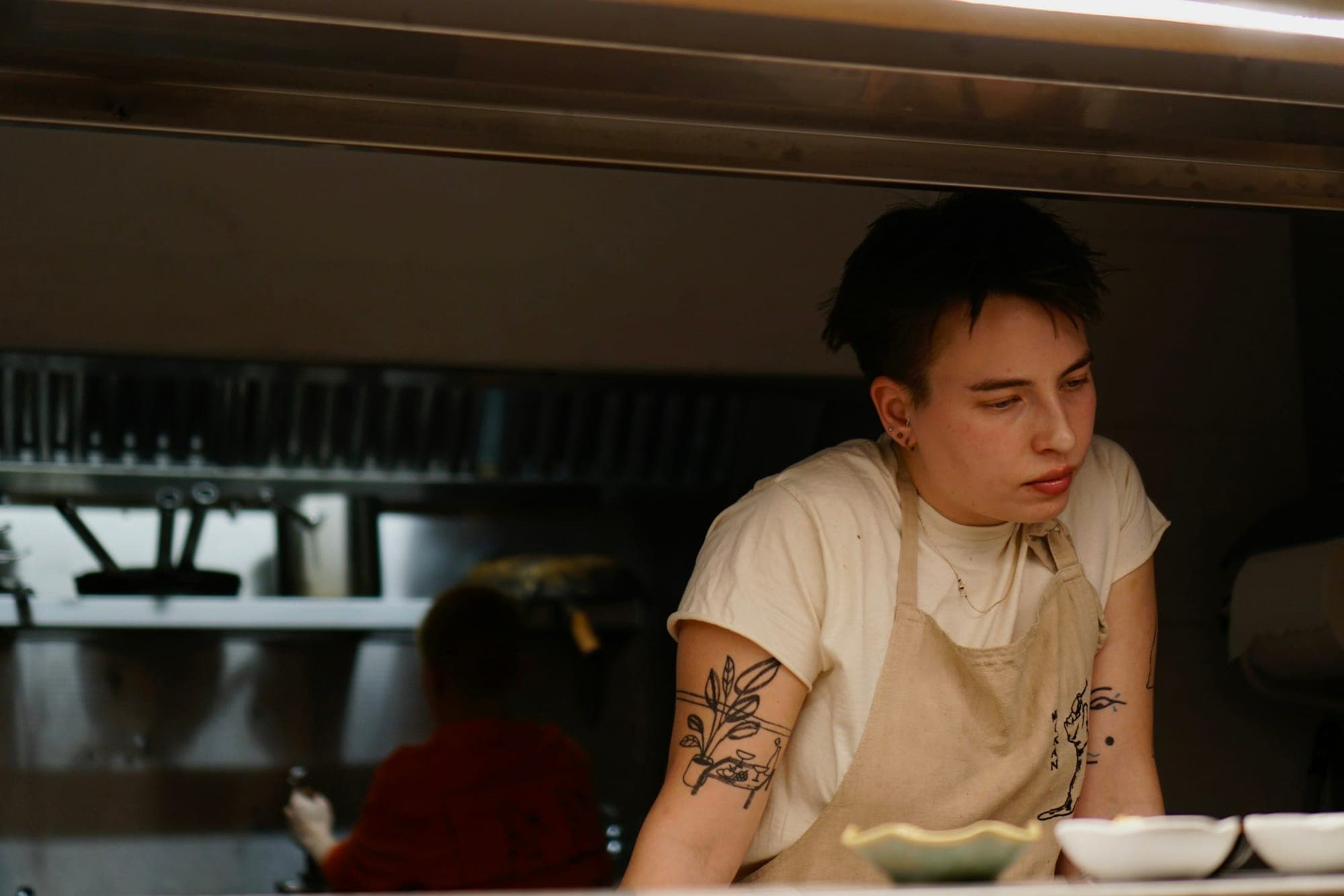 A cook in an apron at the pass of a restaurant kitchen