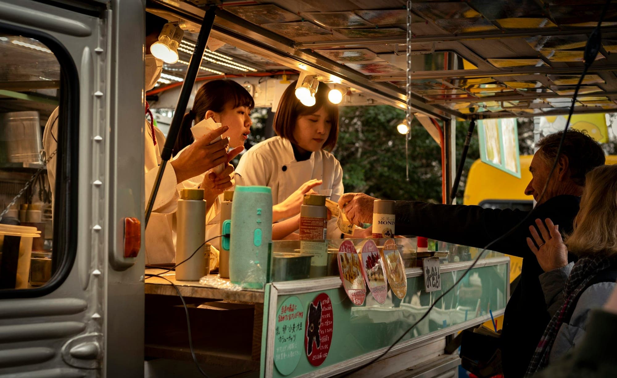 Two cooks serving customers from the hatch of a food truck